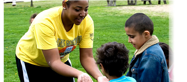 An Indiana State University recreation and sport management student works with children in the daycare program at University Apartments to promote physical activity through a mock olympics. Photographer: Kara Berchem.